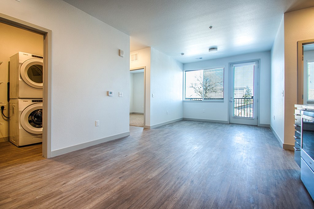 an empty living room and laundry room with washer and dryer