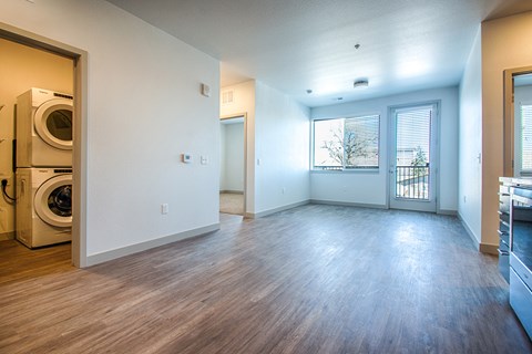 an empty living room and laundry room with washer and dryer