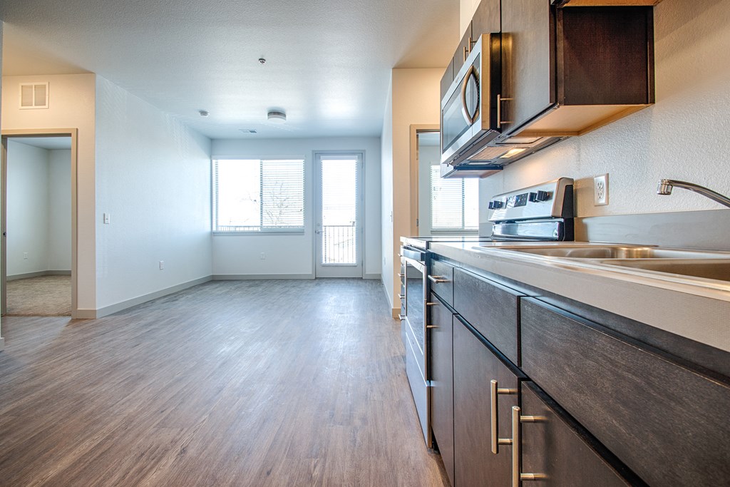 an empty kitchen and living room with wood flooring and a window