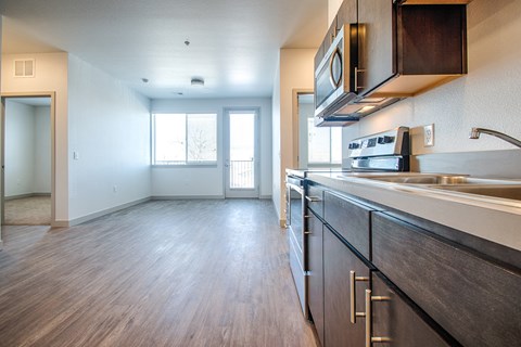 an empty kitchen and living room with wood flooring and a window