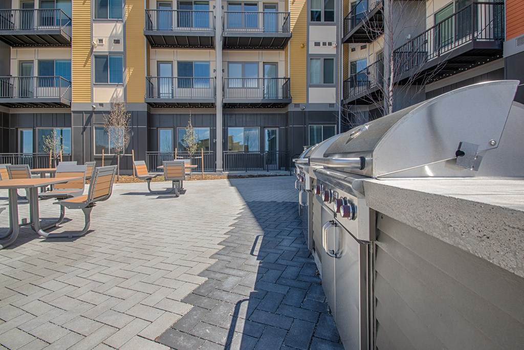 a patio with a barbecue grill and a table with benches