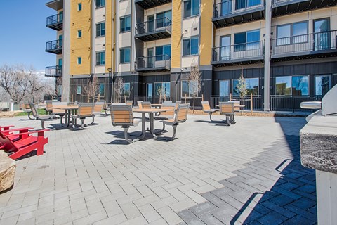 a patio with benches and tables in front of an apartment building