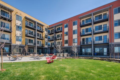 an exterior view of an apartment building with a grassy courtyard