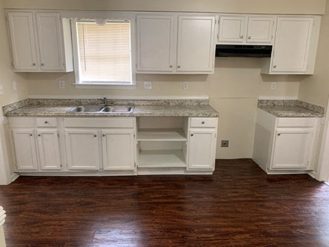 A kitchen with white cabinets and a granite countertop.