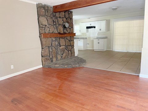 a living room with a stone fireplace and a wooden floor