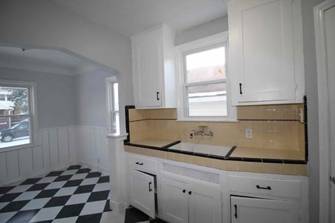 an empty kitchen with white cabinets and a checkered floor