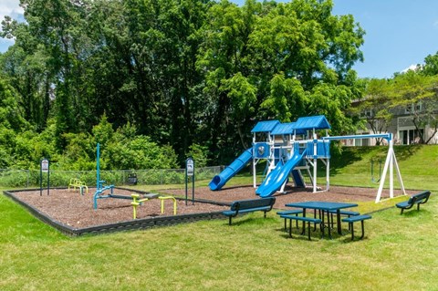 a playground with a slide and picnic table in a park
