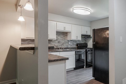 a kitchen with white cabinets and a black refrigerator