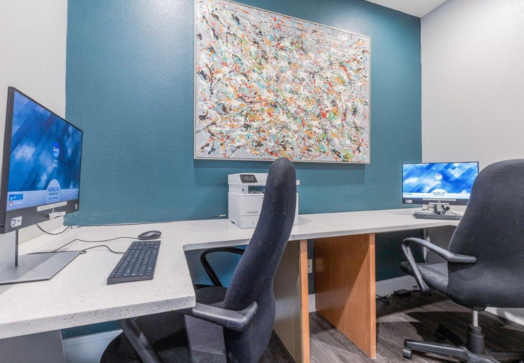 a desk with two computer monitors and a chair