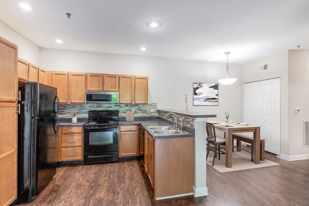 a kitchen with black appliances and a wooden table