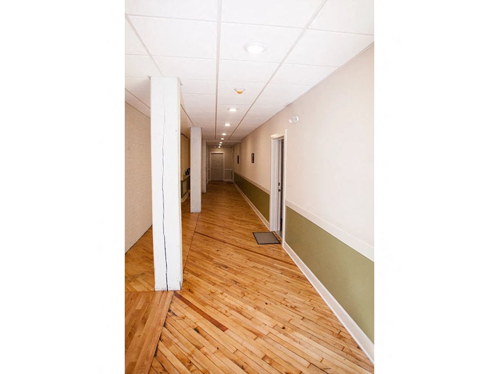 an empty hallway with wood floors and white walls
