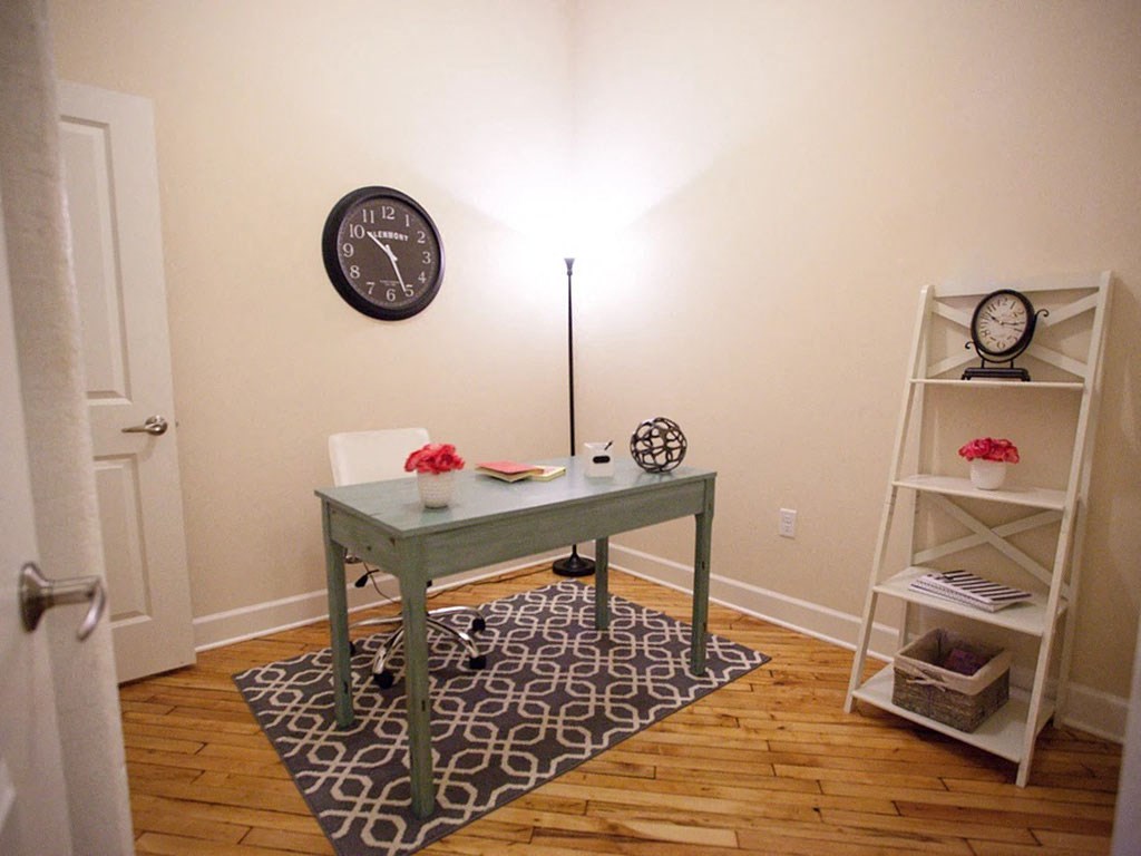 a home office with a green desk and a clock
