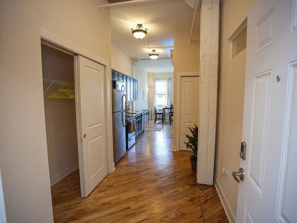 a hallway with a kitchen and a stainless steel refrigerator