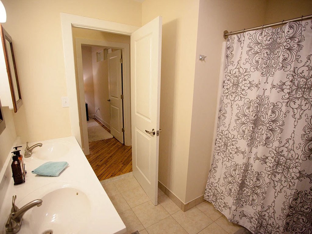 a bathroom with a sink and a shower and a hallway