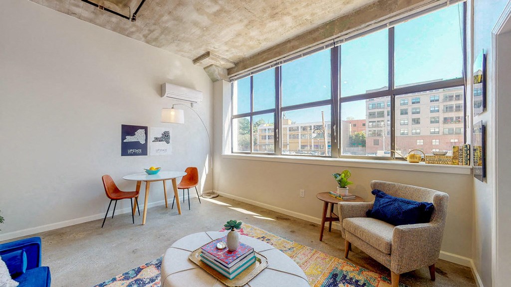 a living room with a large window and a chair and a table