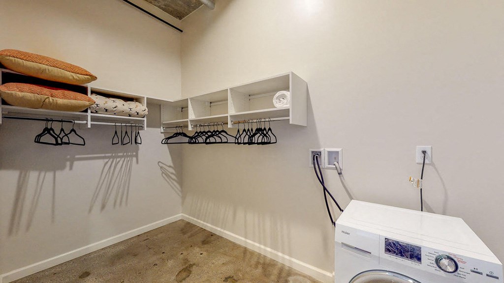a laundry room with a washing machine and shelves on the wall
