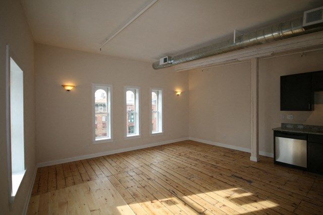 an empty living room with wood floors and a tv