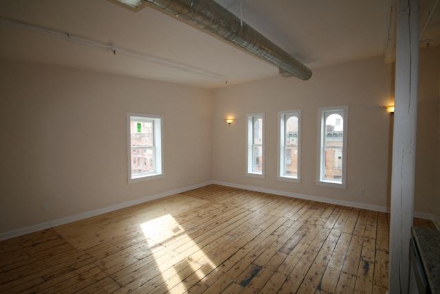 an empty living room with wooden floors and windows