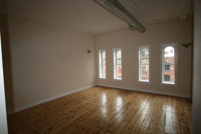 an empty living room with wooden floors and windows