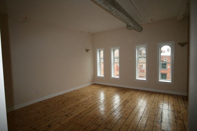 an empty living room with wooden floors and windows