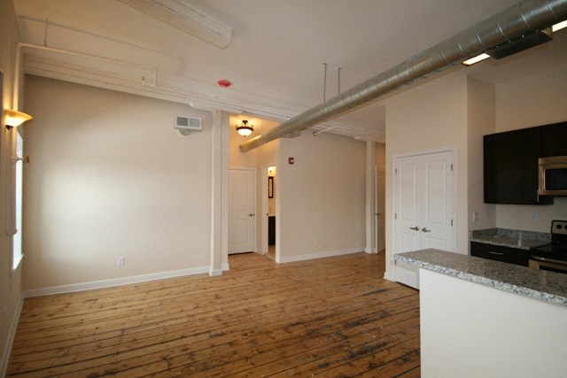 a living room and kitchen with a wood floor and white walls