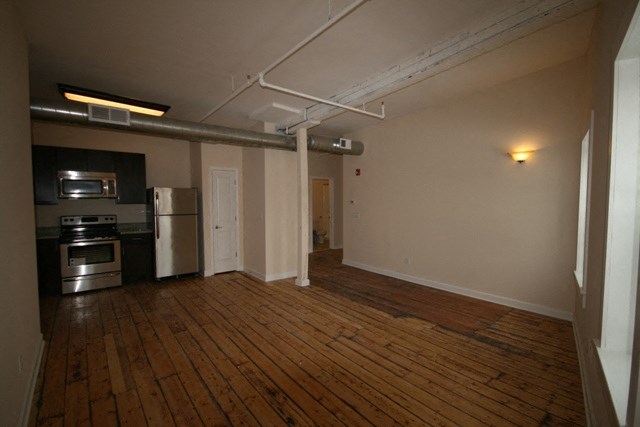an empty living room with wood floors and a stove and refrigerator