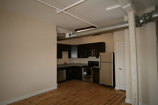 an empty kitchen with black cabinets and a refrigerator