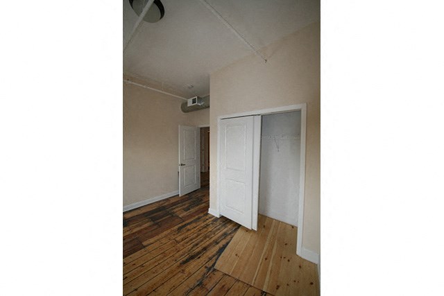 an empty living room with wood floors and a closet