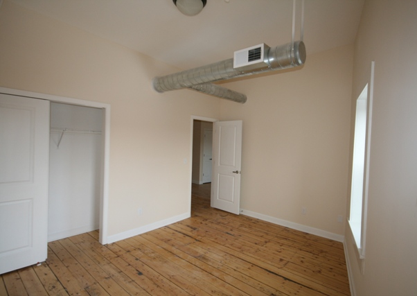 an empty living room with a wood floor and a ceiling fan