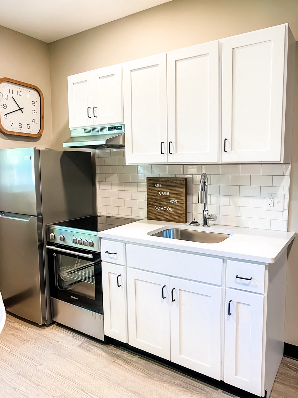a kitchen with white cabinets and a sink and a refrigerator