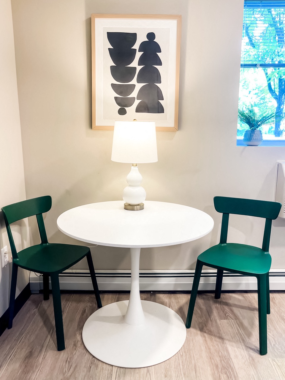 a dining room with a white table and two green chairs
