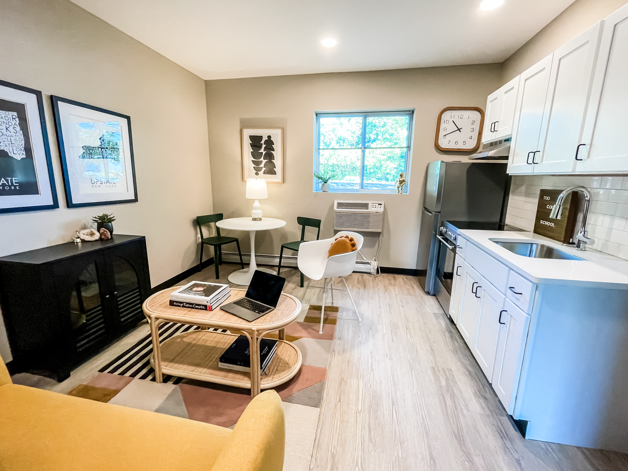 a living room with a kitchen and a table with a laptop