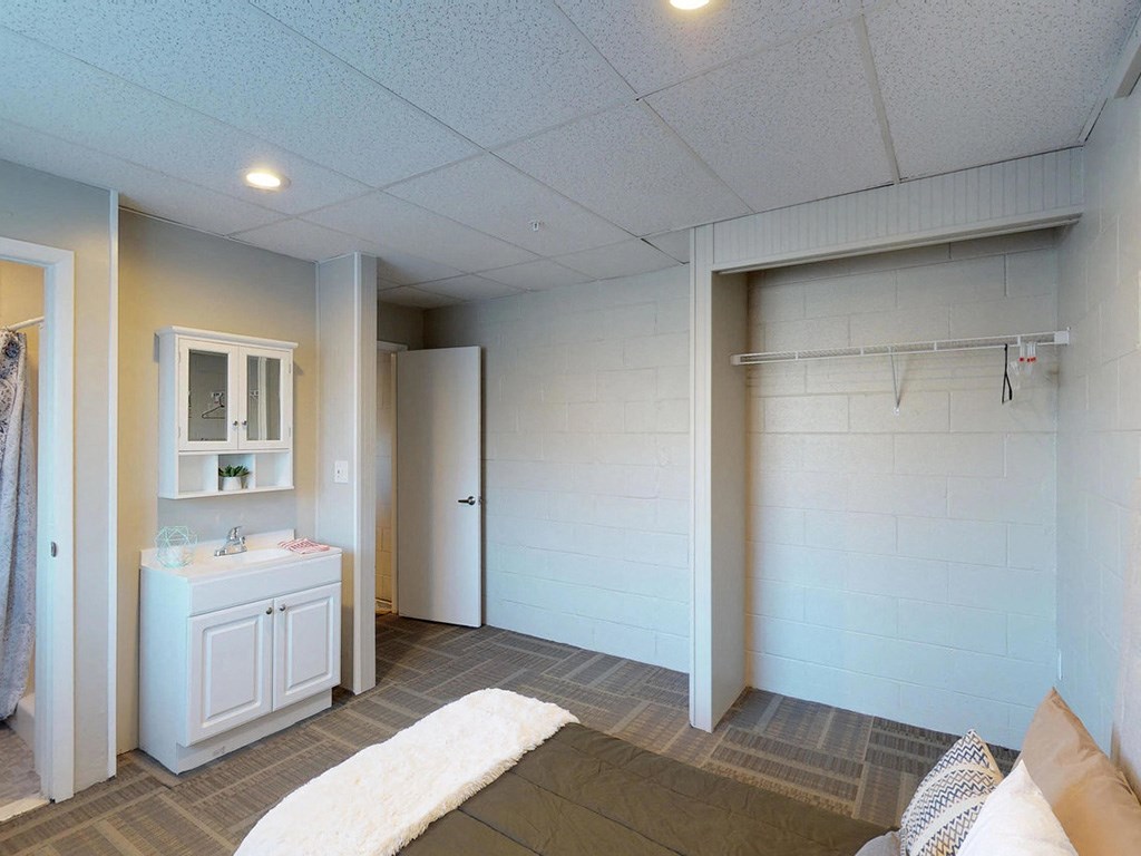 a bedroom with a closet and a bathroom with a sink