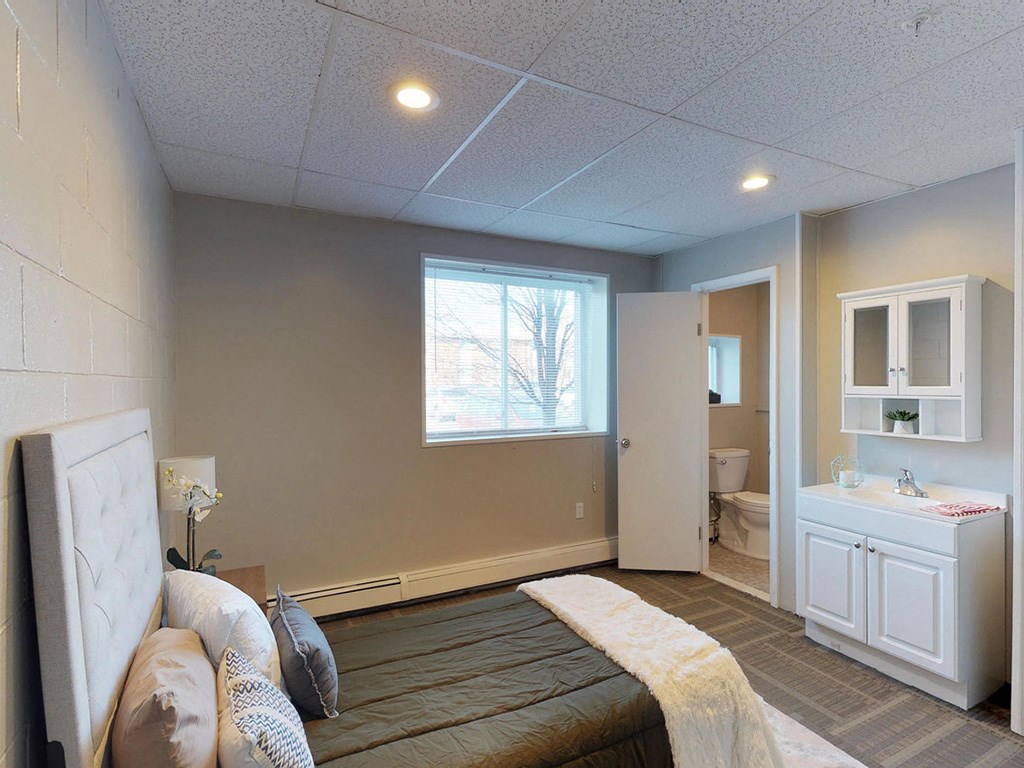 a bedroom with a bed and a bathroom with a sink