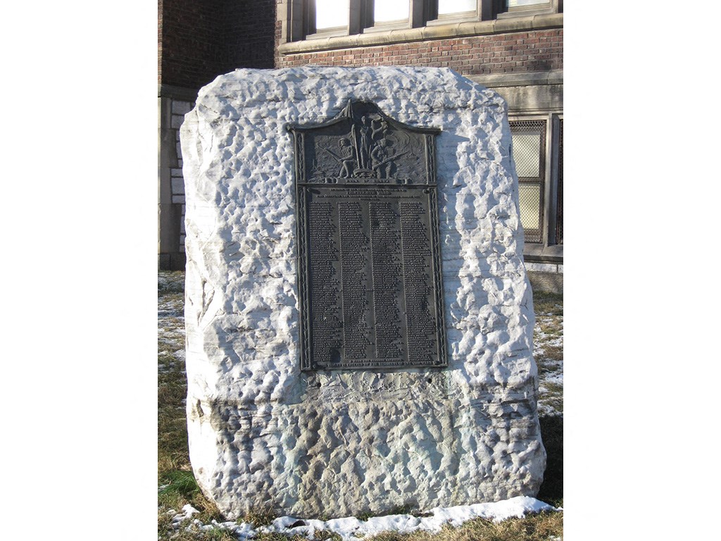 a black door on a stone wall with a building in the background
