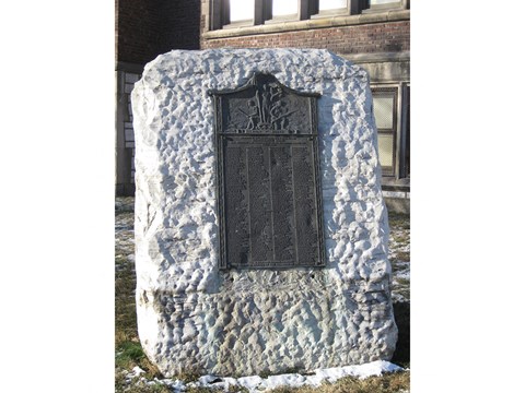 a black door on a stone wall with a building in the background