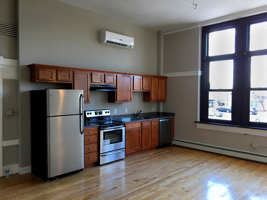 an empty kitchen with stainless steel appliances and wooden cabinets