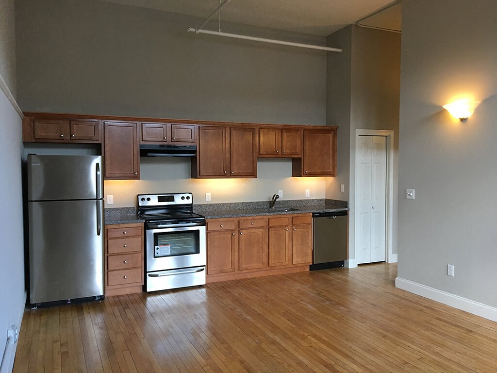 an empty kitchen with wooden floors and stainless steel appliances