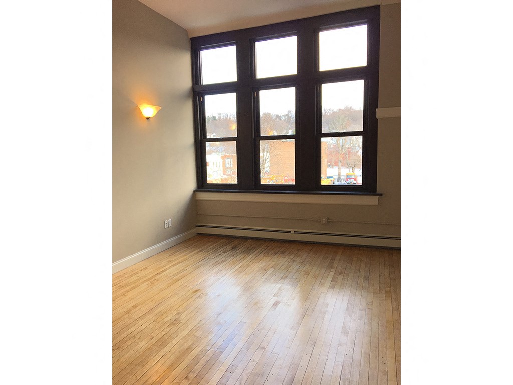 an empty living room with large windows and wood floors