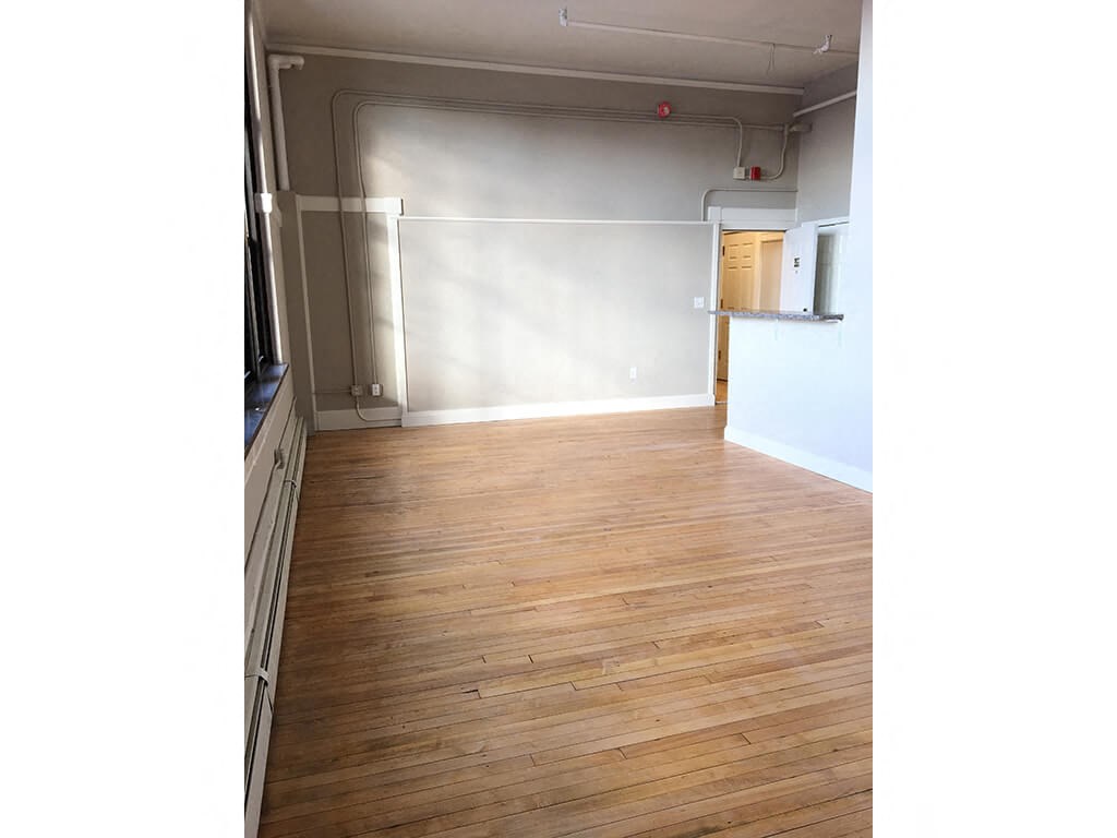 an empty room with white walls and a wood floor