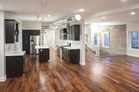 an open kitchen and living room with wood floors and black cabinets