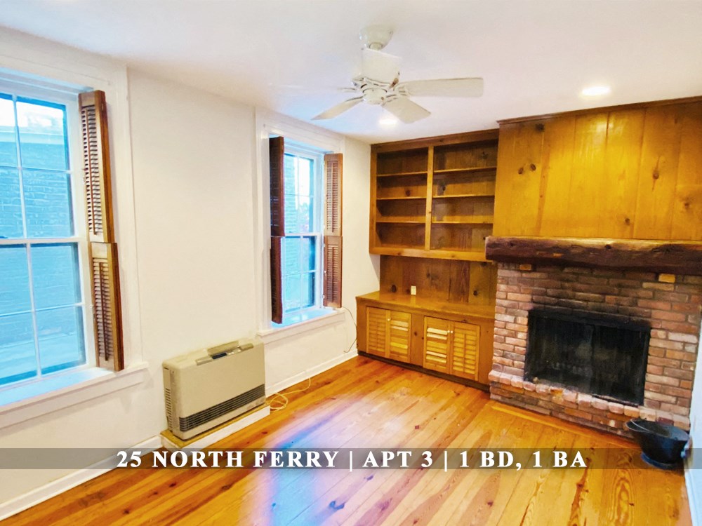 an empty living room with a brick fireplace and a book shelf