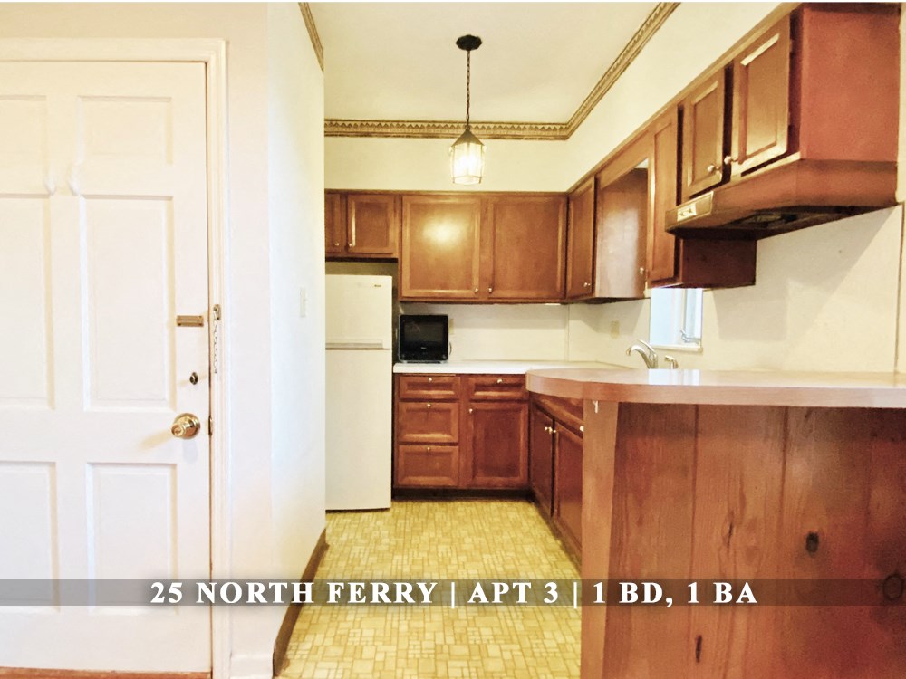 an empty kitchen with wooden cabinets and a white door