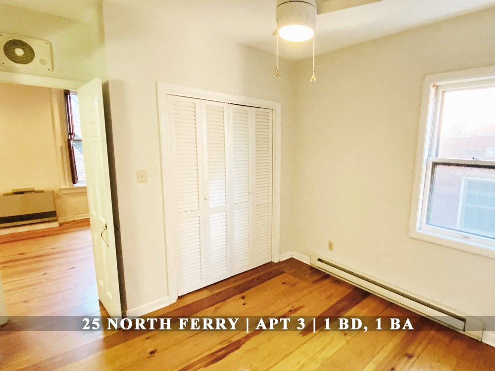 an empty living room with wooden floors and white shutters