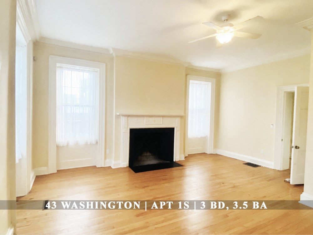 an empty living room with a fireplace and a ceiling fan
