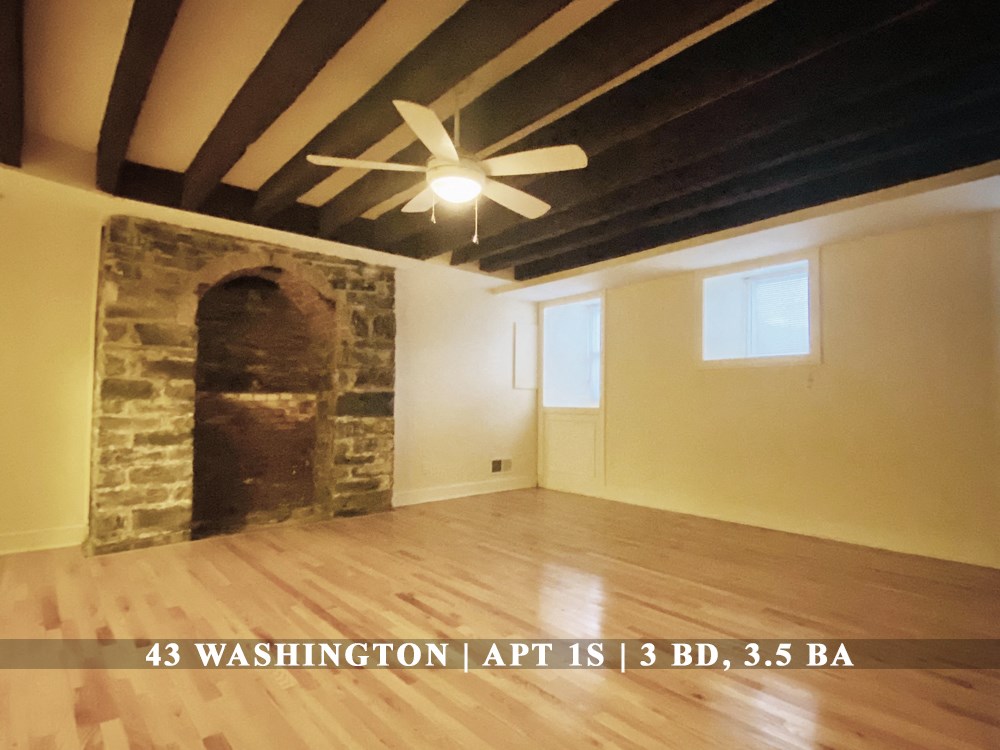 an empty living room with a ceiling fan and a stone fireplace