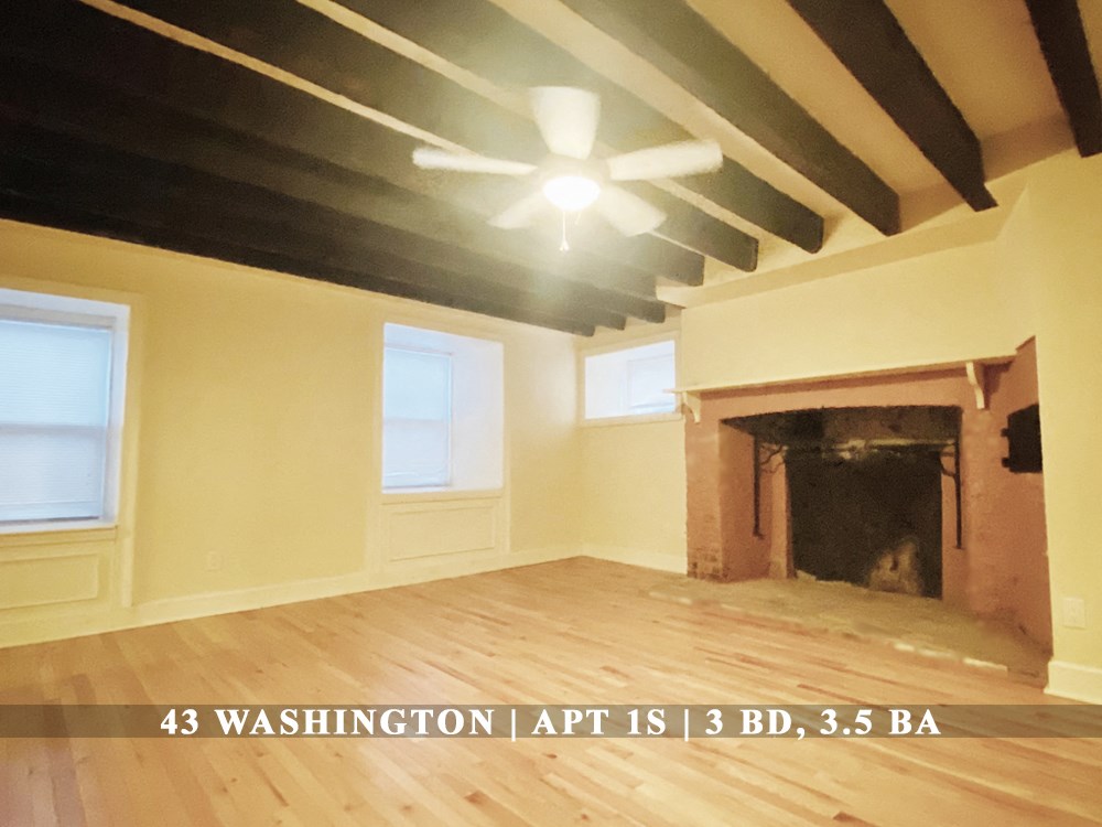 an empty living room with a fireplace and a ceiling fan