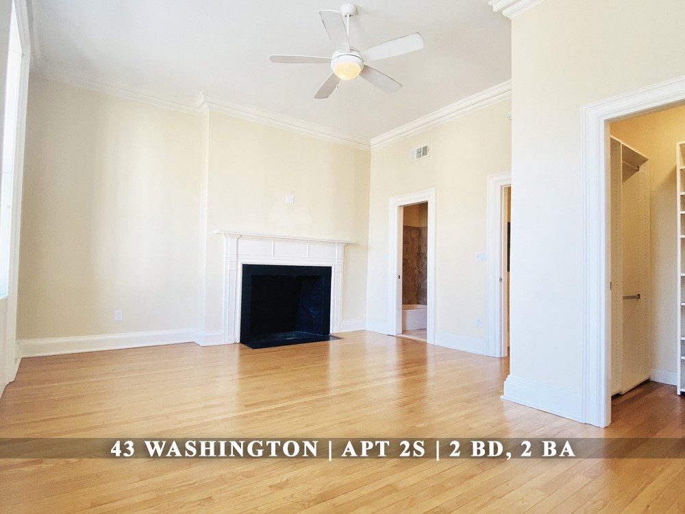 an empty living room with a fireplace and a ceiling fan