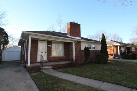 A red brick house with a white door and a small front porch.