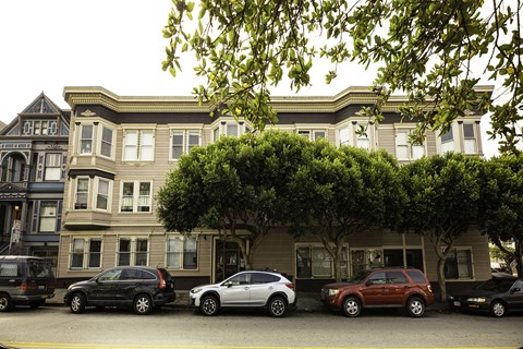 A row of cars are parked in front of a building.